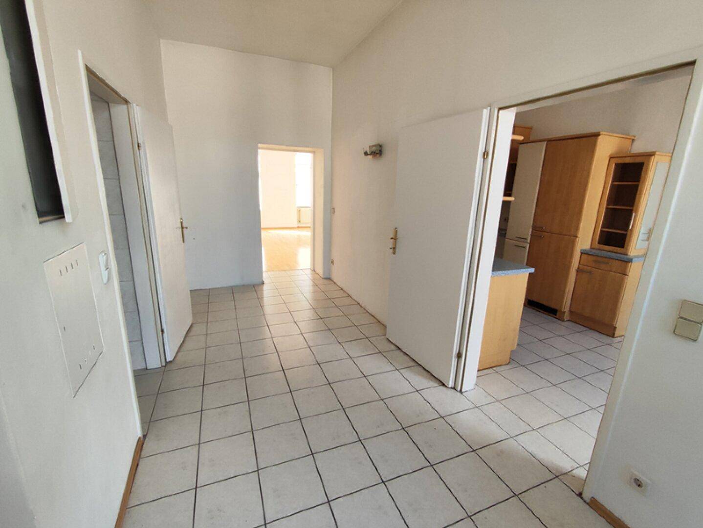 Heller Flur mit Fliesenboden, der zu weiteren Zimmern der Wohnung führt.