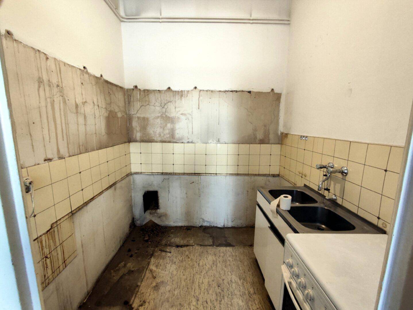 Renovierungsbedürftige Küche mit alten Fliesen und Spüle, bietet Potenzial für eine Neugestaltung.