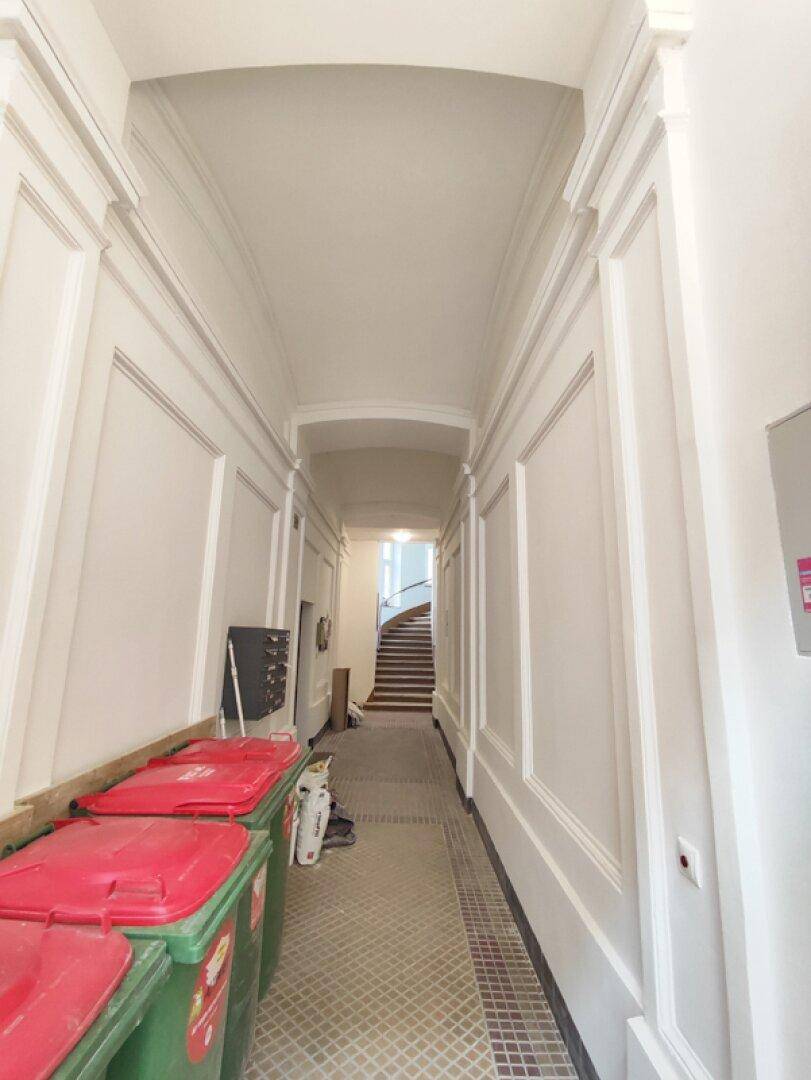 Geräumiger Eingangsbereich mit hohen Decken und gemustertem Fliesenboden, führt zum Treppenhaus.