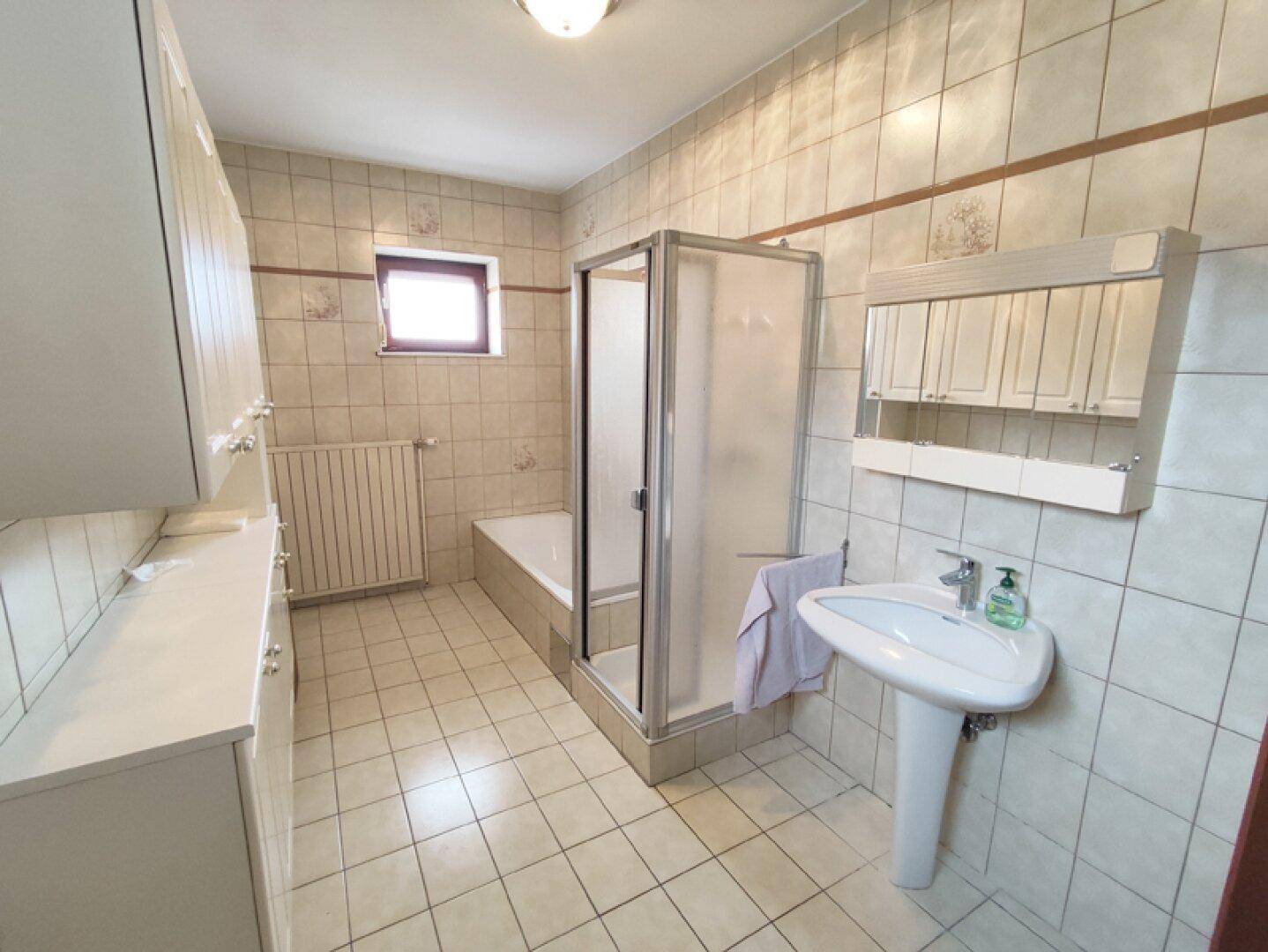 Badezimmer mit Badewanne, Duschkabine, Waschbecken und Spiegelschrank.