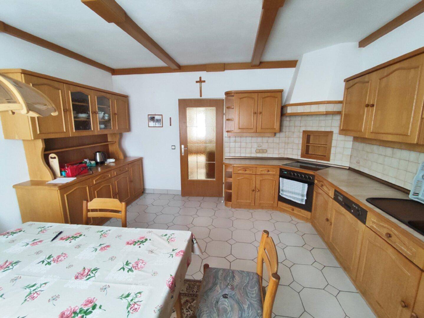 Funktionale Küche mit Holzfronten, Fliesenboden und integrierten Geräten.