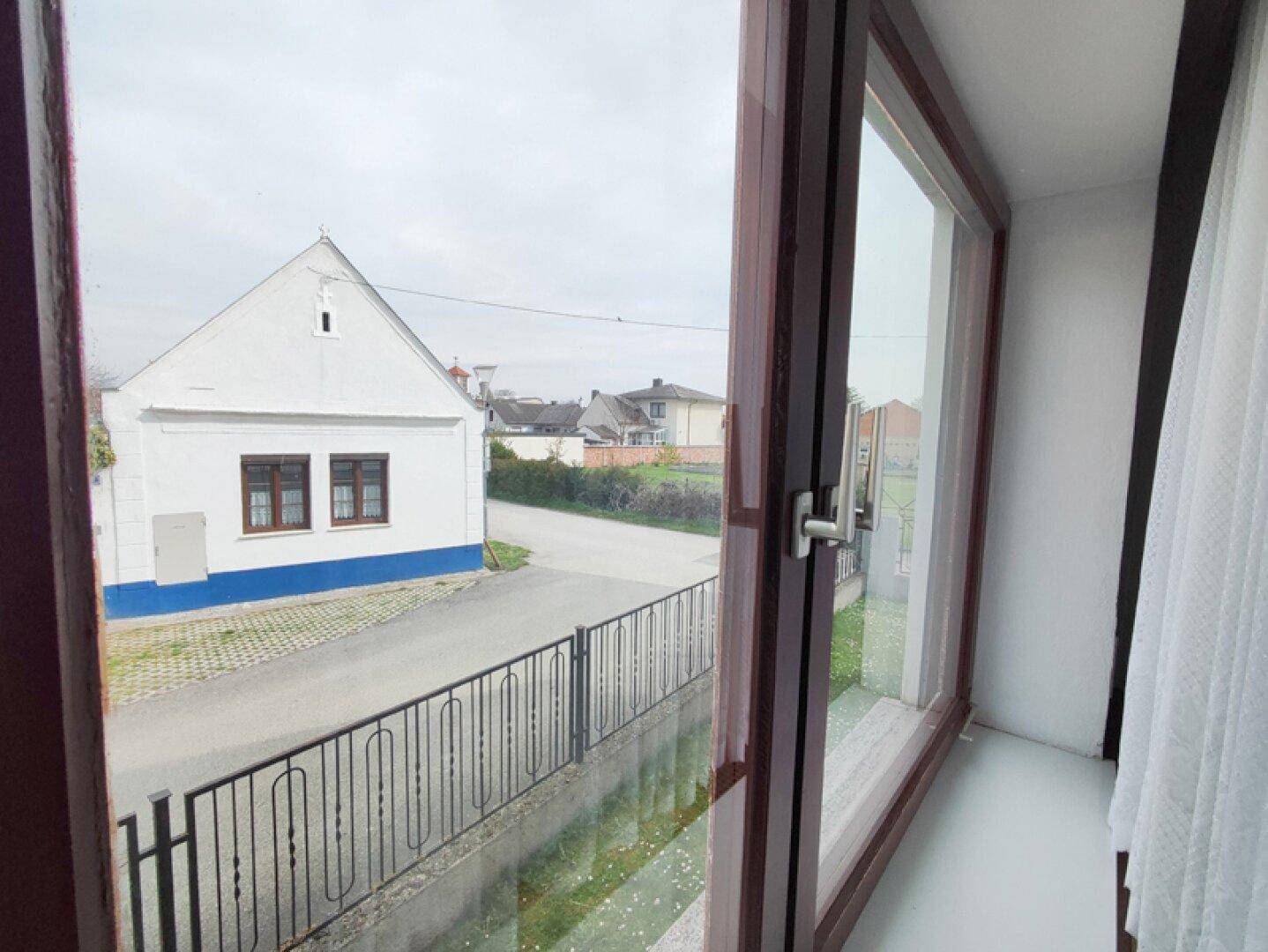 Blick aus dem Fenster auf die Straße und ein gegenüberliegendes Haus.