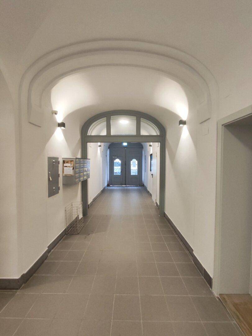 Heller und langer Flur im Eingangsbereich mit gewölbter Decke und Fliesenboden.