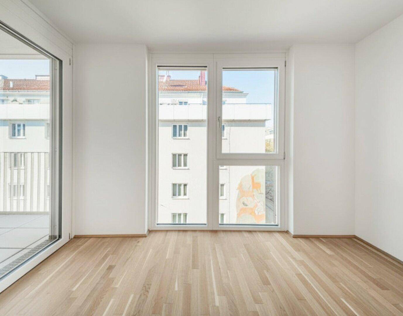 Lichtdurchflutetes, leeres Zimmer mit Holzboden und großen Fenstern, die einen Blick nach draußen bieten.