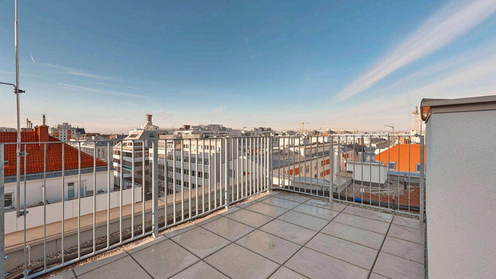 Geräumige Dachterrasse mit Fliesenboden und Metallgeländer bietet einen weiten Stadtblick.