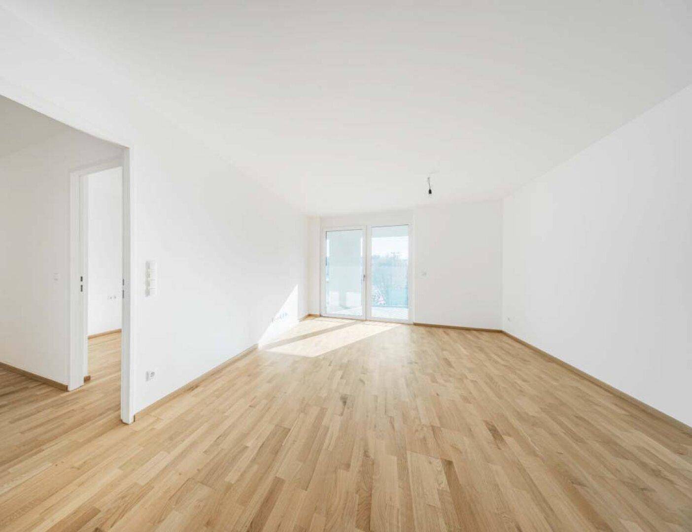 Geräumiges, helles Zimmer mit Holzboden und großen Fenstern, bereit zur individuellen Gestaltung.