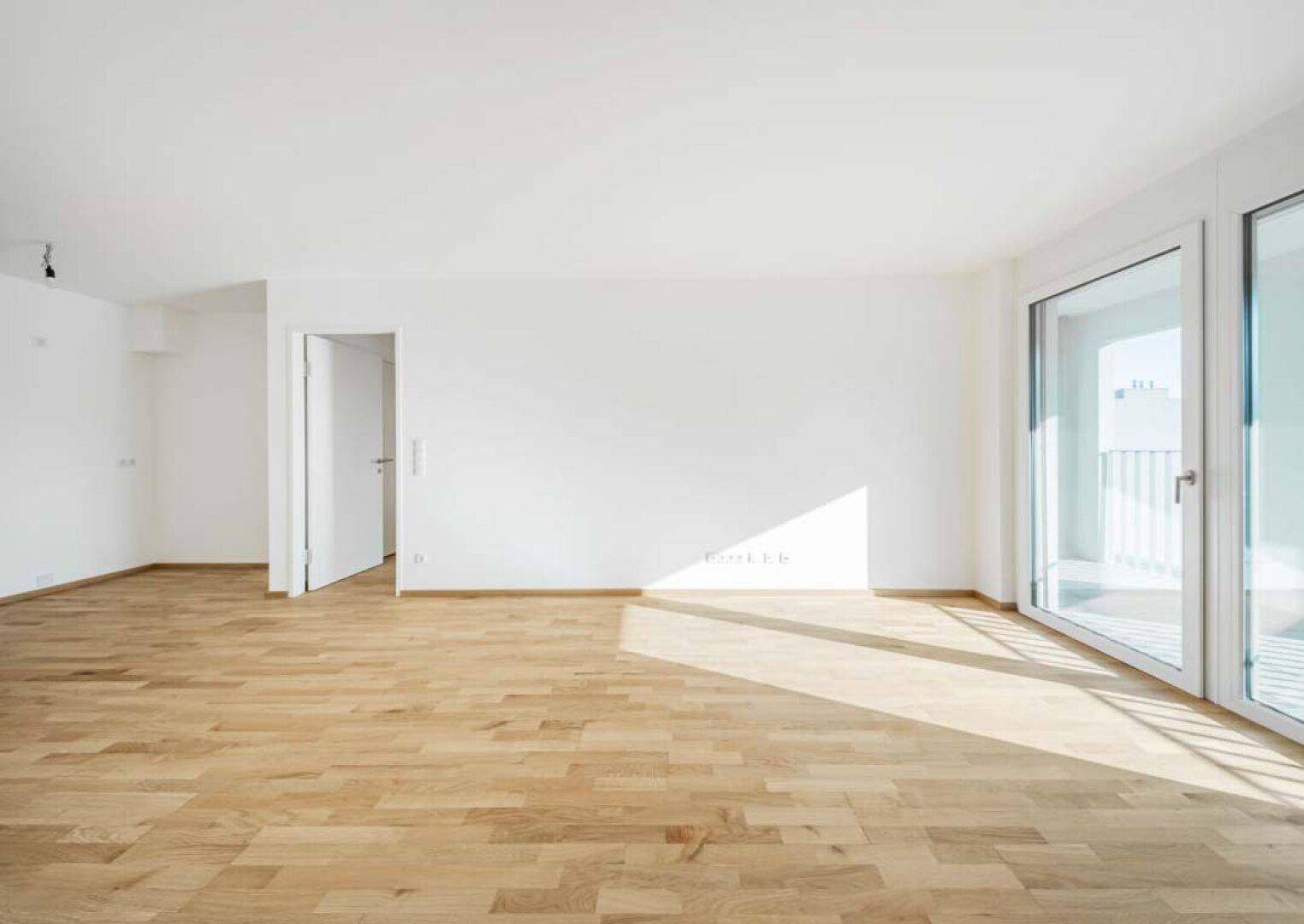 Heller Wohnbereich mit Holzboden und Zugang zu einem Balkon, ideal für entspannte Stunden.