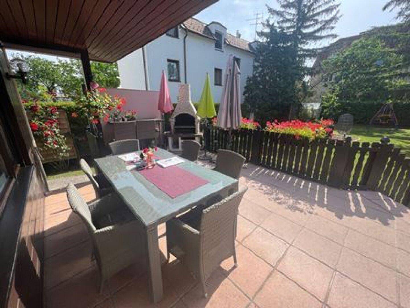 Gemütliche Terrasse mit Essbereich, Sonnenschirmen und integriertem Grill für gesellige Abende.