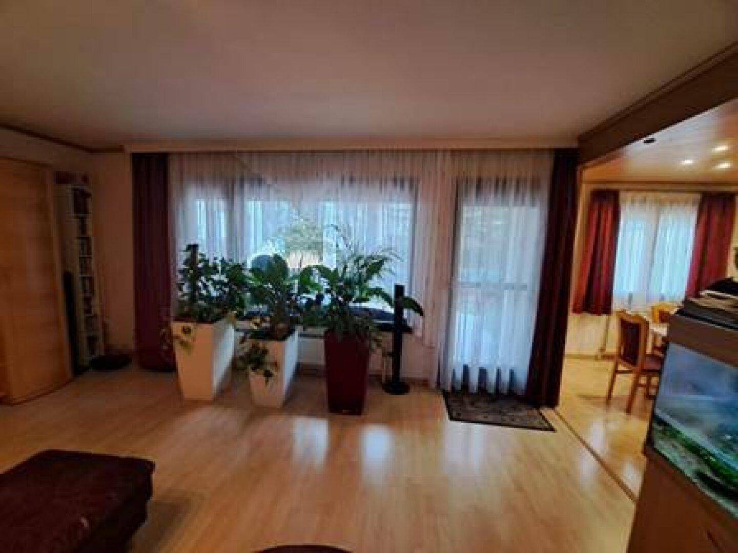 Geräumiger Wohnbereich mit viel Tageslicht, Parkettboden und Zugang zum Esszimmer.