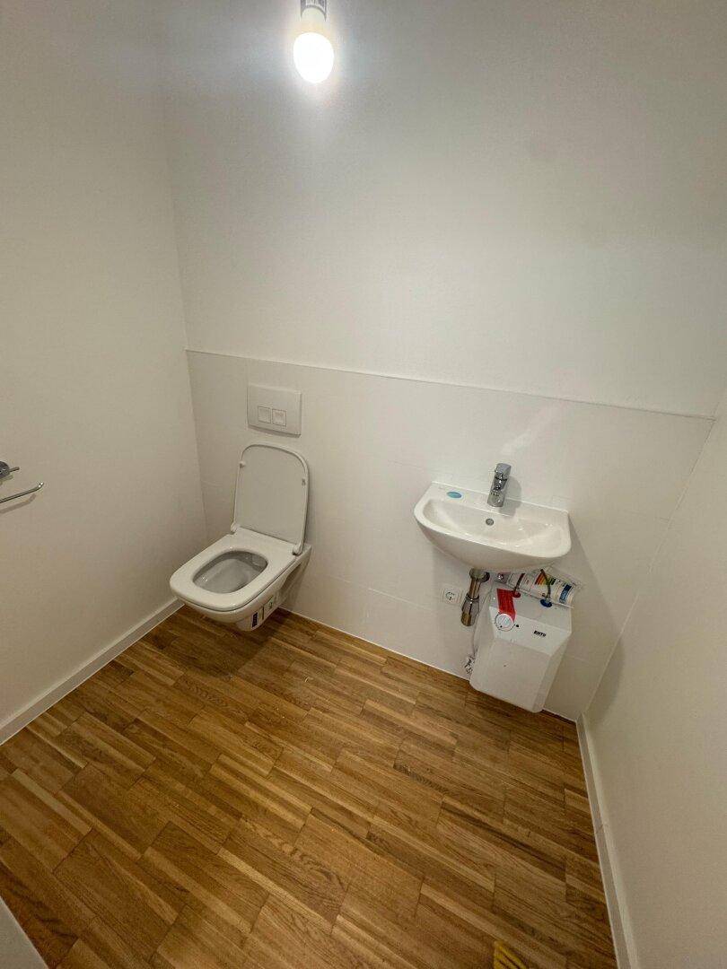 Kleine, saubere Toilette mit wandhängendem WC und einem kompakten Waschbecken.