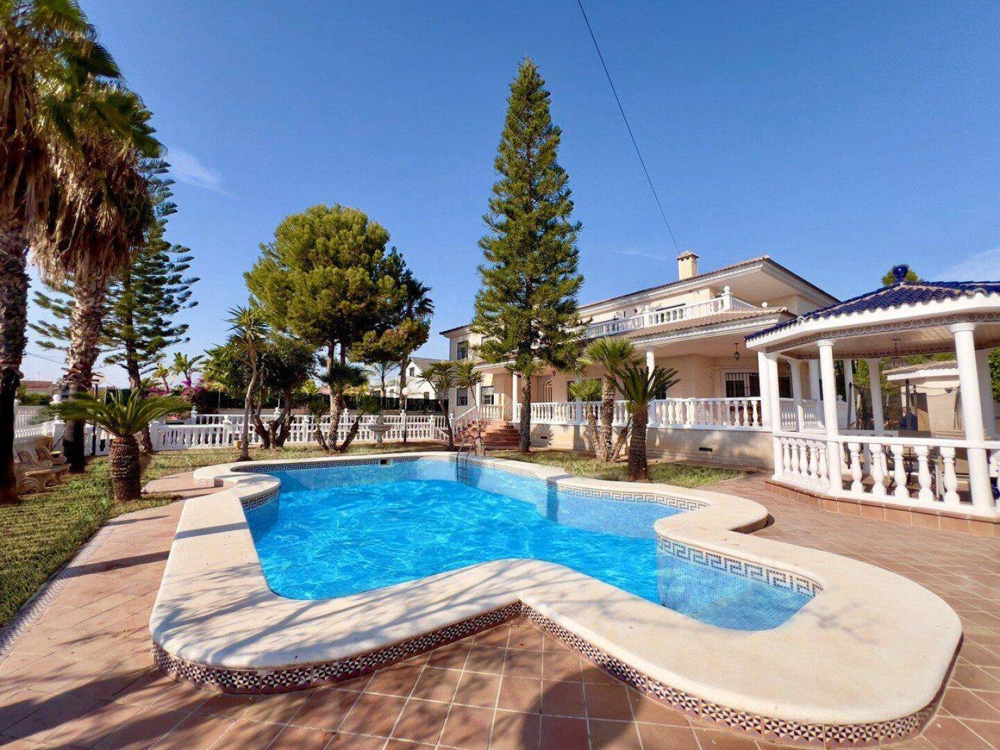 Weitläufiger Außenbereich mit großem Pool, gepflegtem Rasen und dem Haupthaus im Hintergrund.