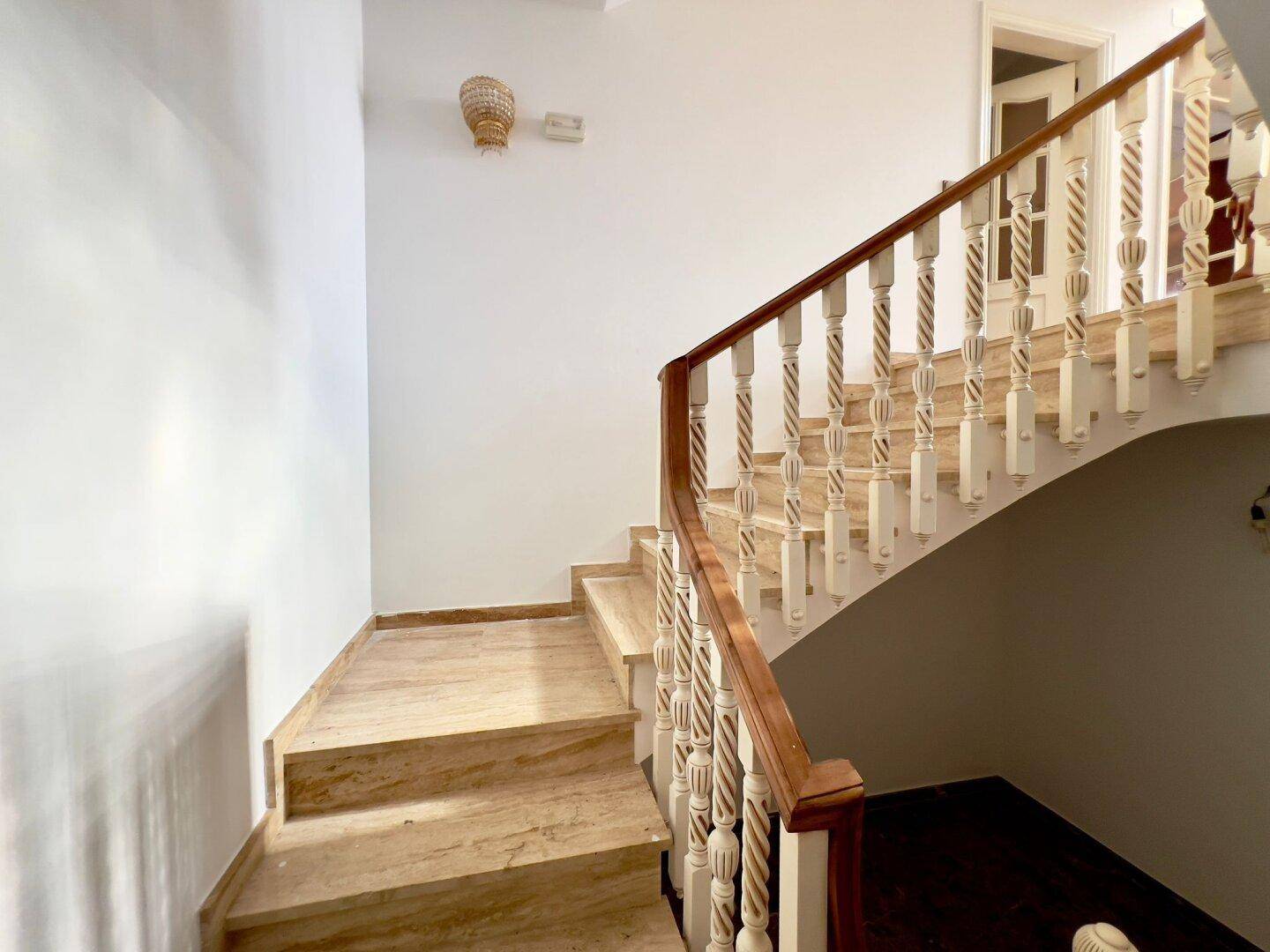 Die geschwungene Treppe mit Marmorstufen und einem kunstvoll gedrechselten Holzgeländer.