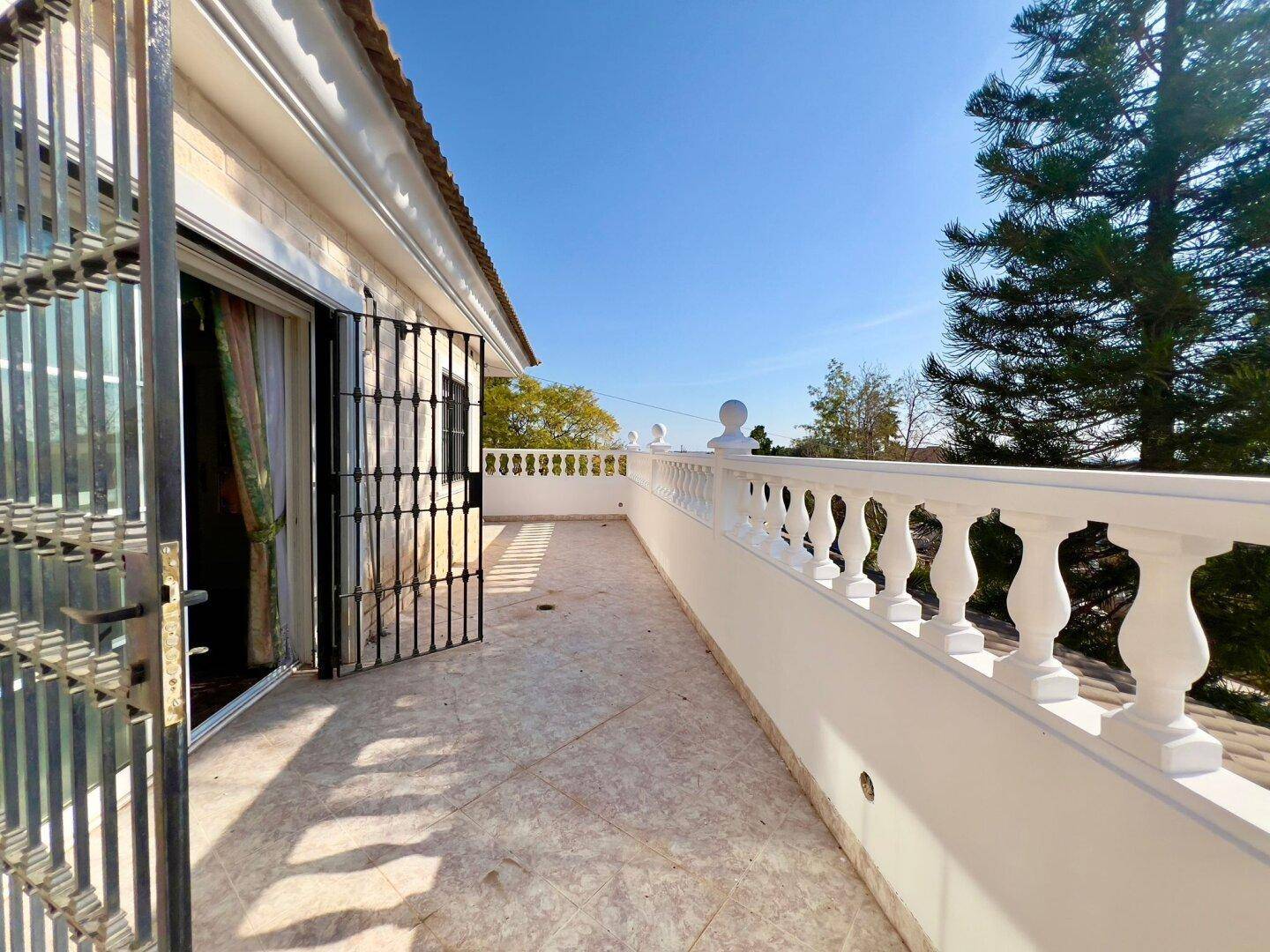 Sonniger Balkon mit Fliesenboden und einer klassischen Balustrade, der einen weiten Blick bietet.