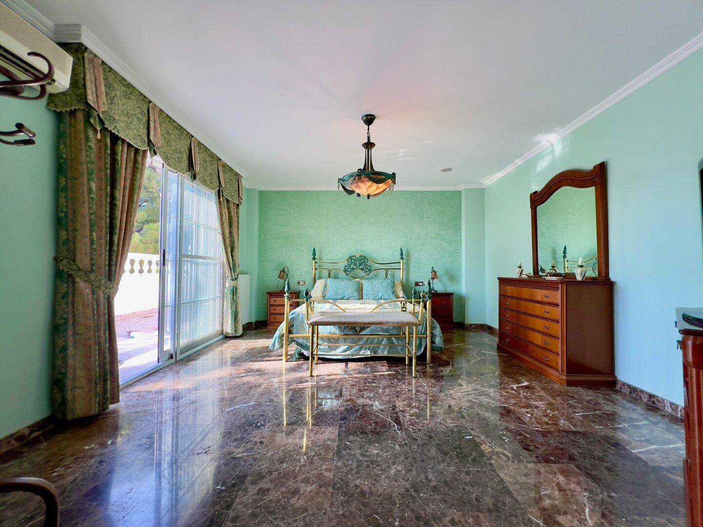 Geräumiges Schlafzimmer mit grünen Wänden, glänzendem Marmorboden und Zugang zum Balkon.