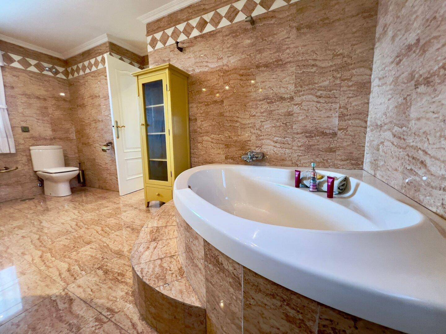Große, eingebaute Badewanne in einem traditionell gefliesten Badezimmer mit warmen Farbtönen.