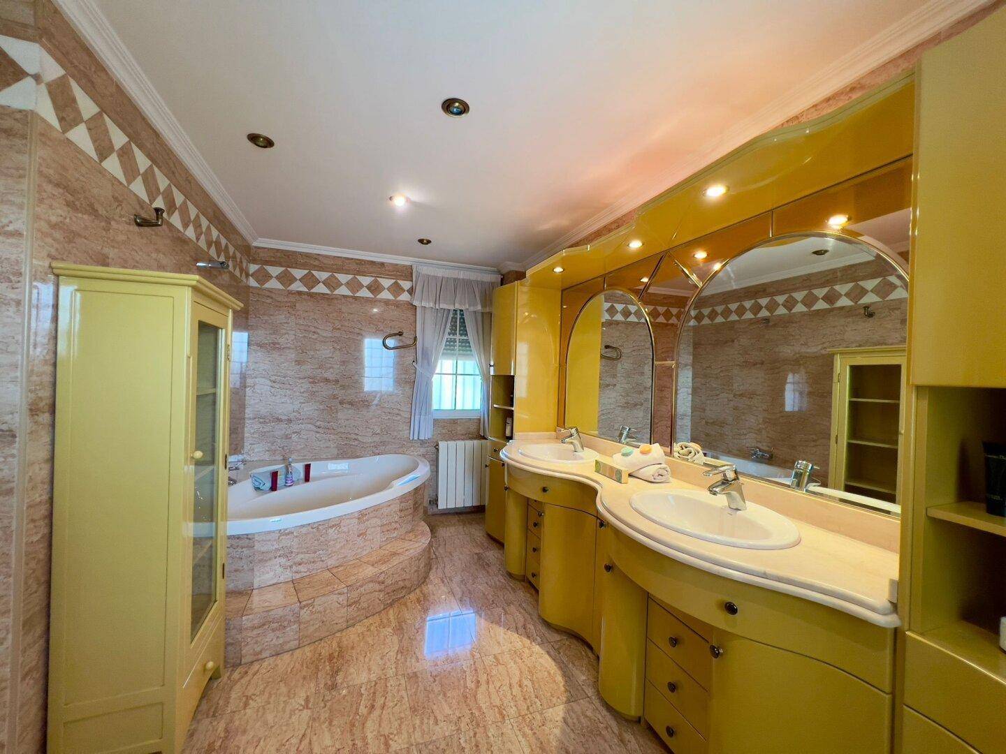 Luxuriöses Badezimmer mit Doppelwaschbecken, großer Badewanne und Bidet in warmen Farbtönen.