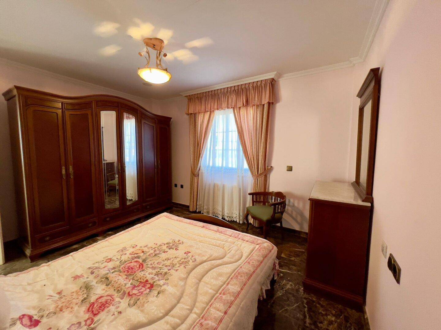 Gemütliches Schlafzimmer mit rosa Wänden, glänzendem Marmorboden und klassischem Holzmobiliar.