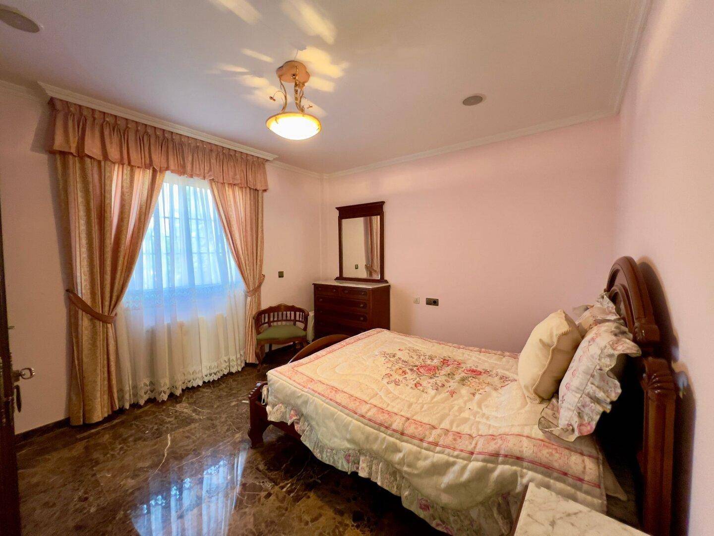 Schlafzimmer mit Fenster, das viel Tageslicht hereinlässt, und traditioneller Einrichtung.