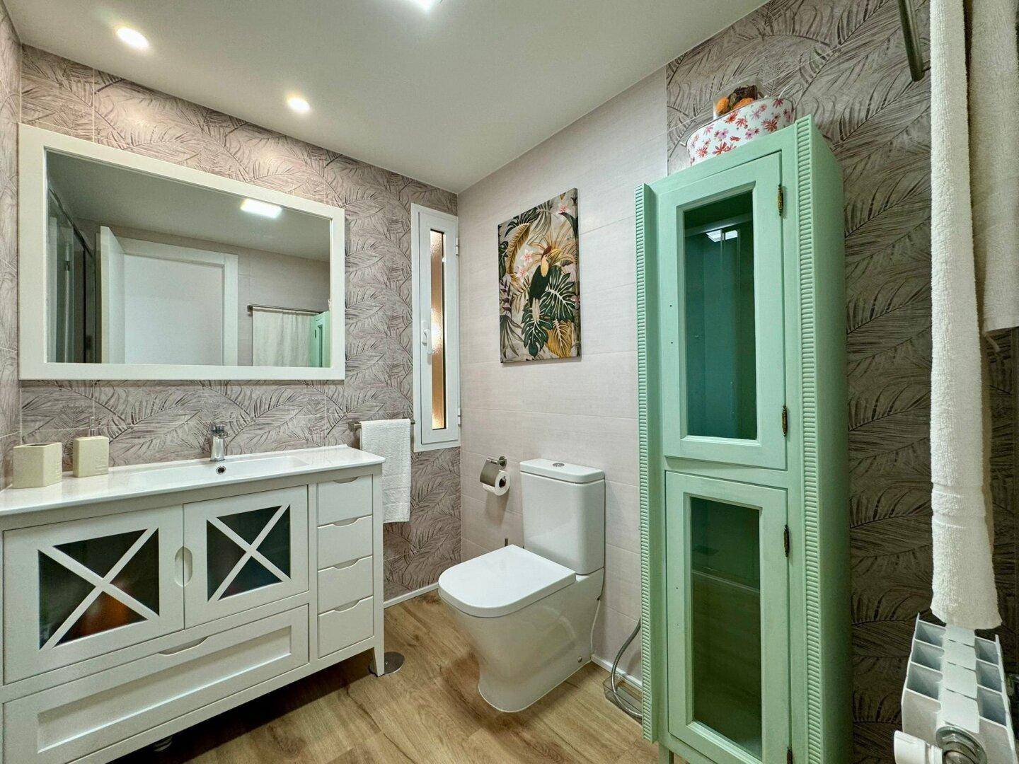 Modernes Badezimmer mit Waschtisch, Toilette und dekorativen Wandfliesen im tropischen Stil.