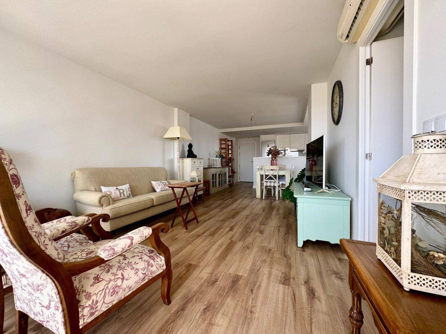 Gemütlicher Wohnbereich mit Sofa, Holzboden und offenem Übergang zum Ess- und Küchenbereich.