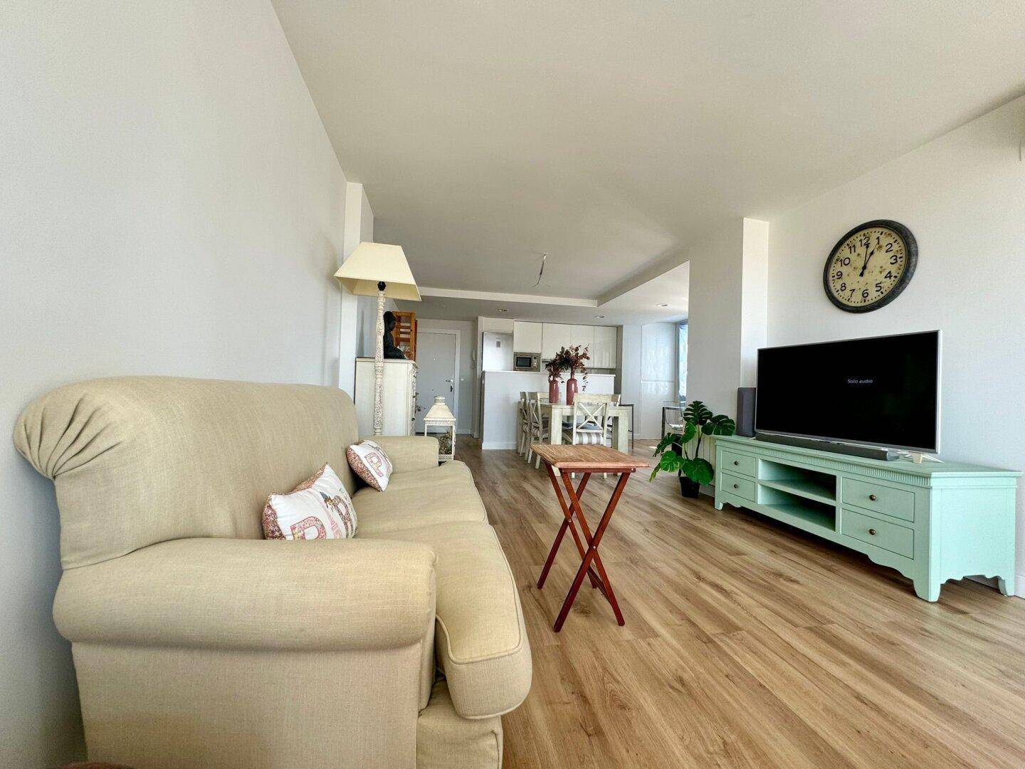 Geräumiger Wohnbereich mit beigem Sofa, Holzboden und Blick auf den offenen Essbereich.
