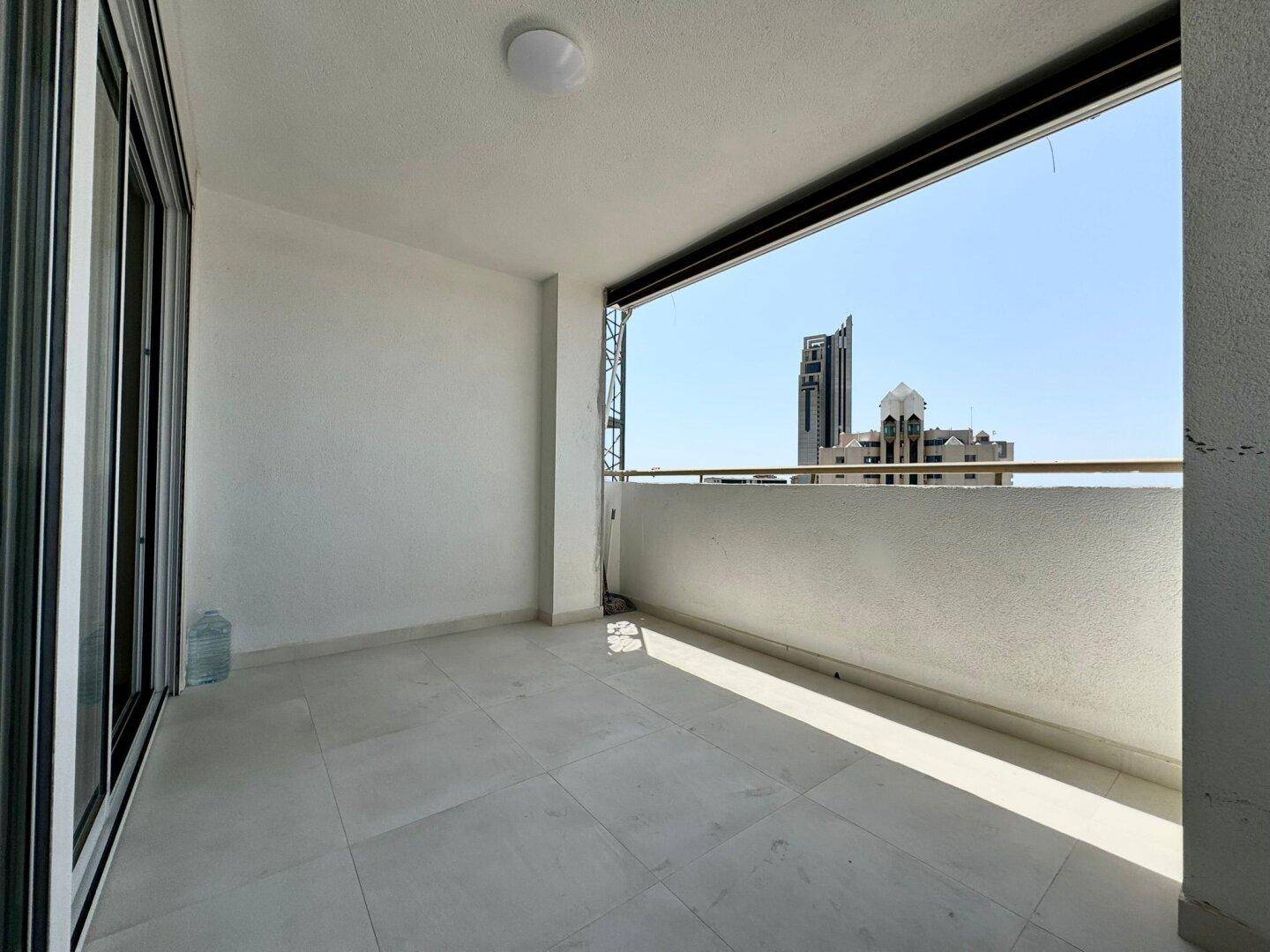 Leerer Balkon mit Fliesenboden und weitem Blick auf die umliegenden Gebäude.