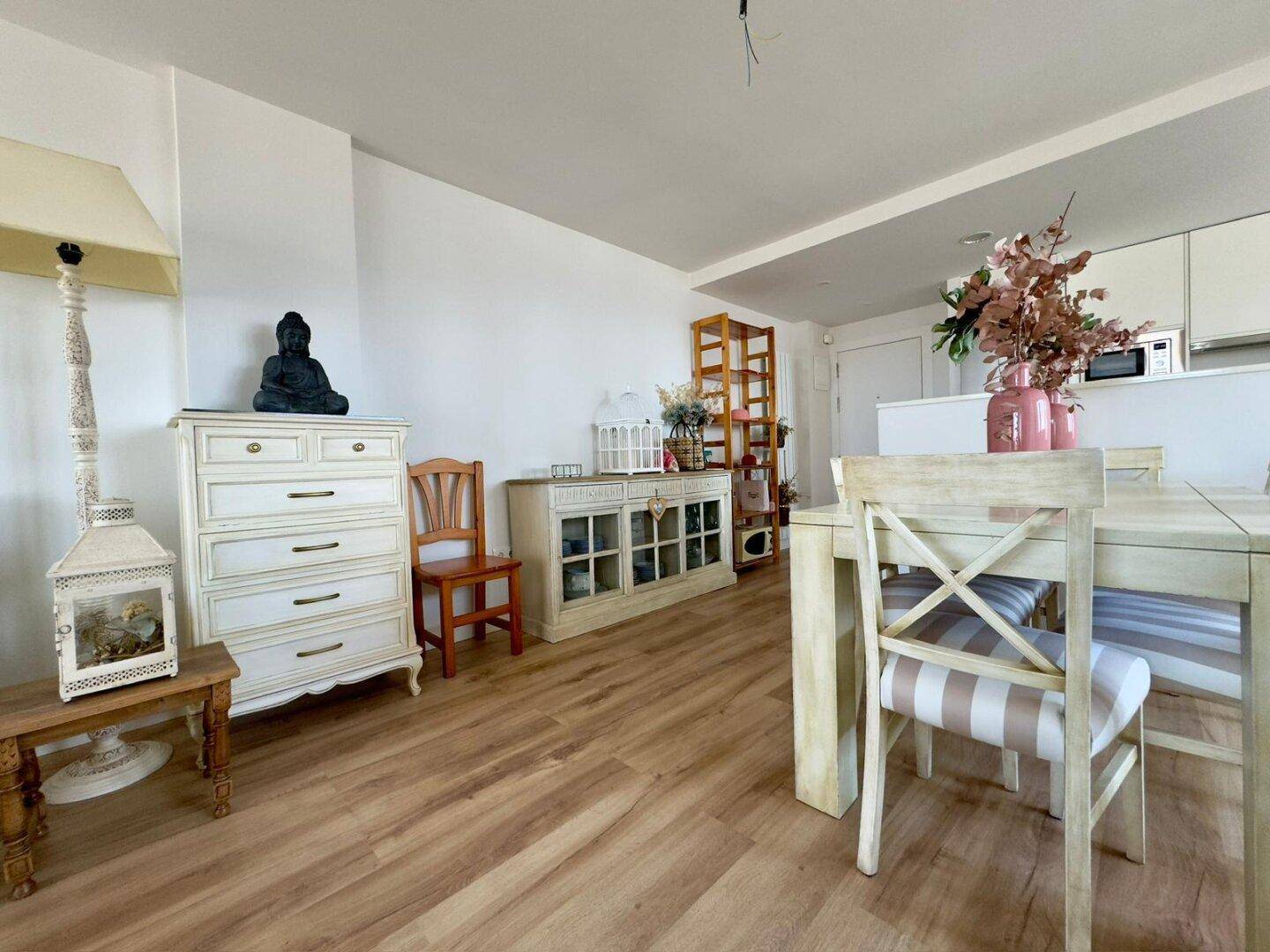 Heller Essbereich mit Holztisch, passenden Stühlen und dekorativen Möbeln auf Holzboden.