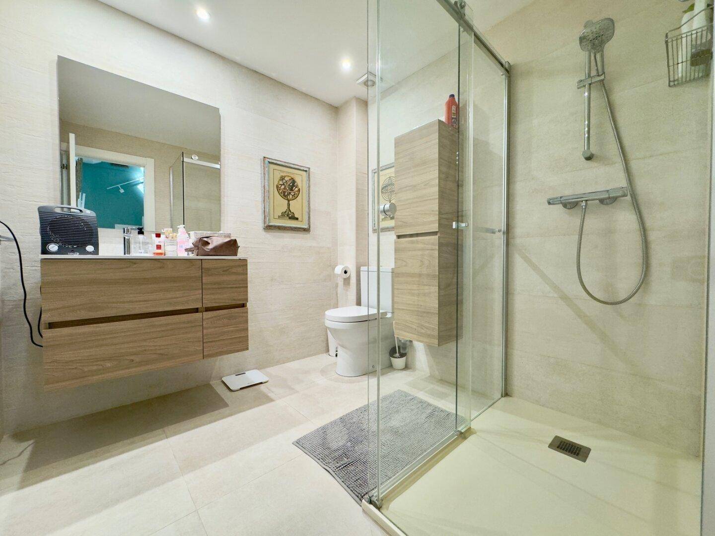 Zeitgemäßes Badezimmer mit Glasdusche, schwebendem Waschtisch und großem Spiegel.