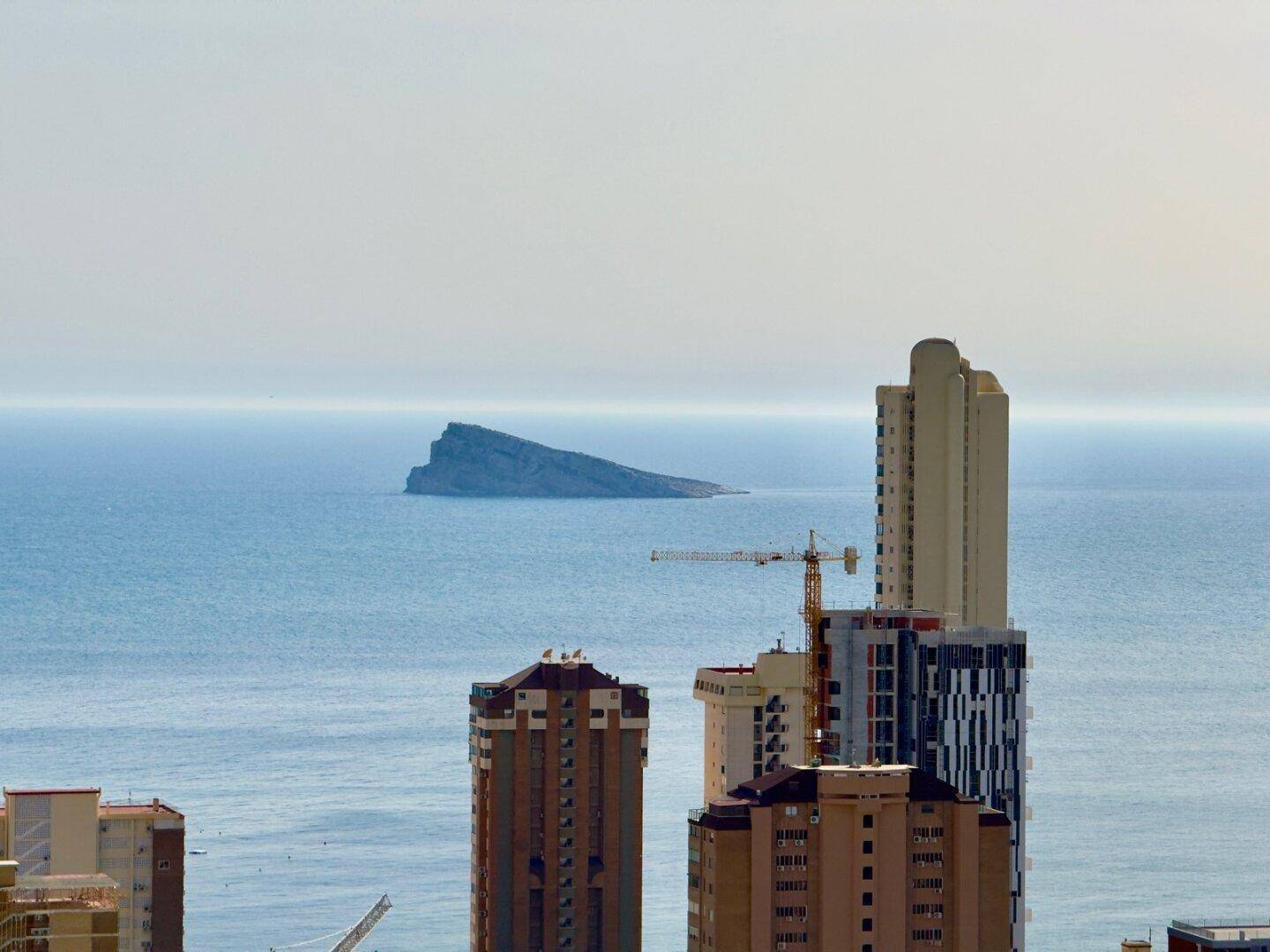 Weitläufiger Blick auf die Küstenstadt mit Hochhäusern und dem Meer.