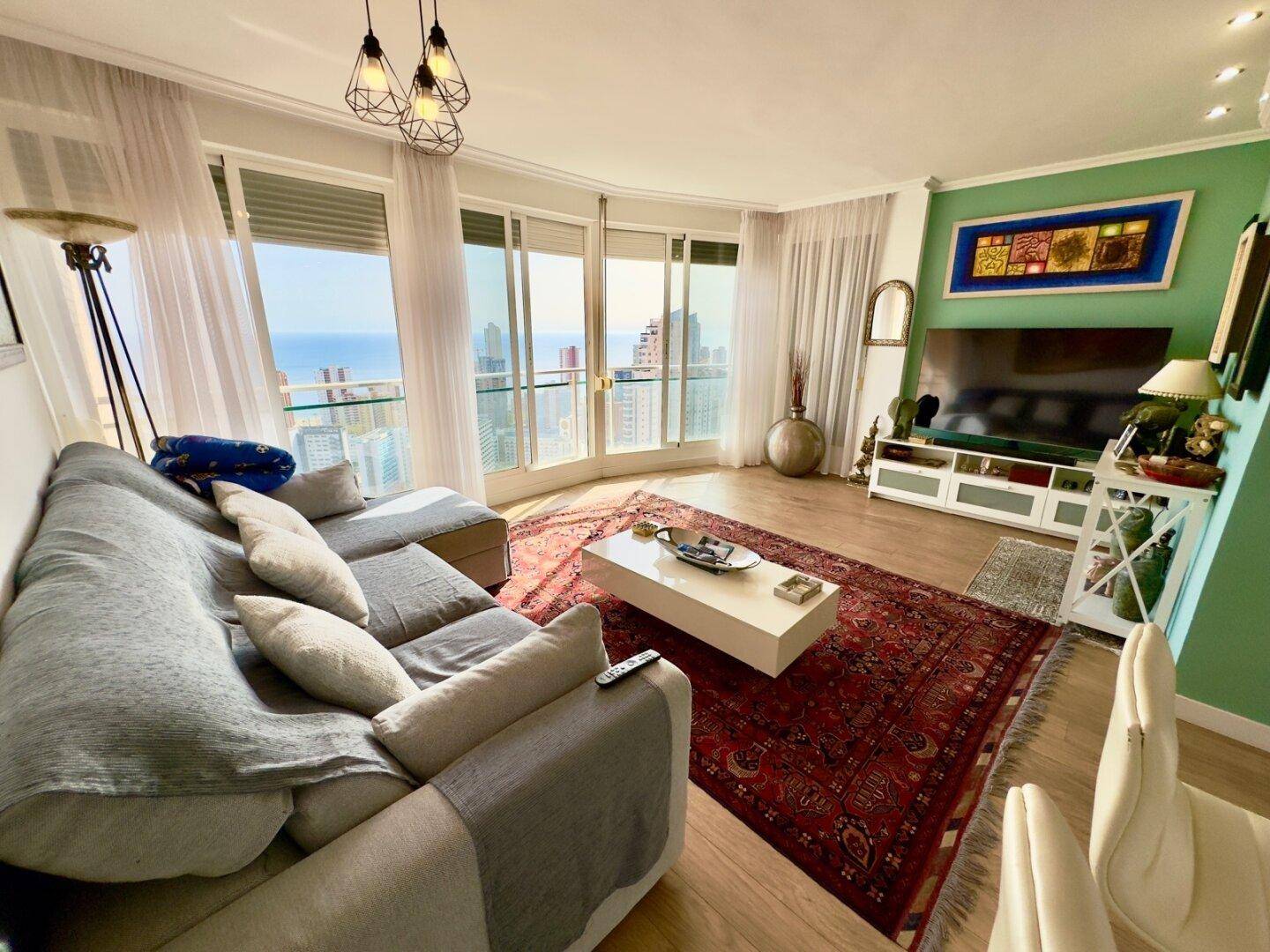Gemütliches Wohnzimmer mit Sofa, Couchtisch und beeindruckendem Meerblick durch große Fenster.