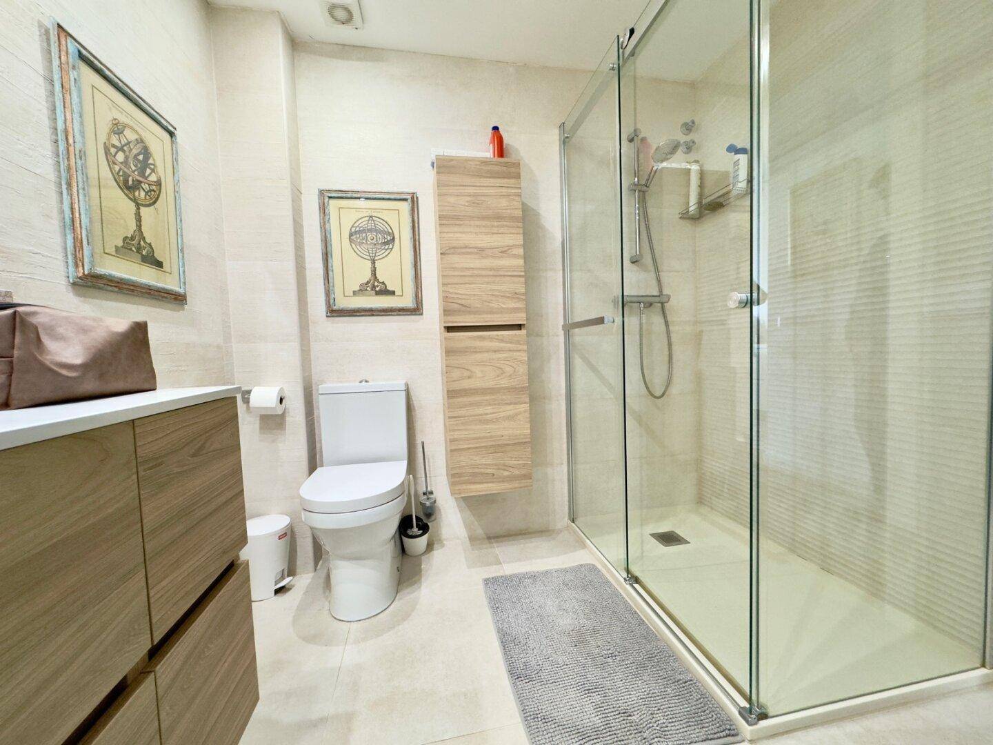 Modernes Badezimmer mit begehbarer Dusche, WC und Holzwaschtisch.