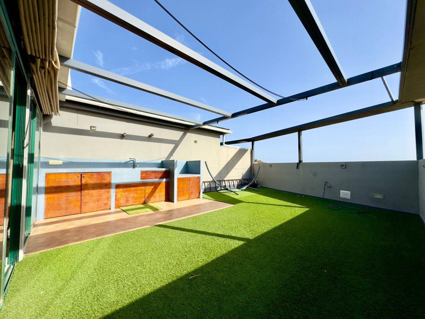 Große Dachterrasse mit Kunstrasen, Außenküche und Meerblick.
