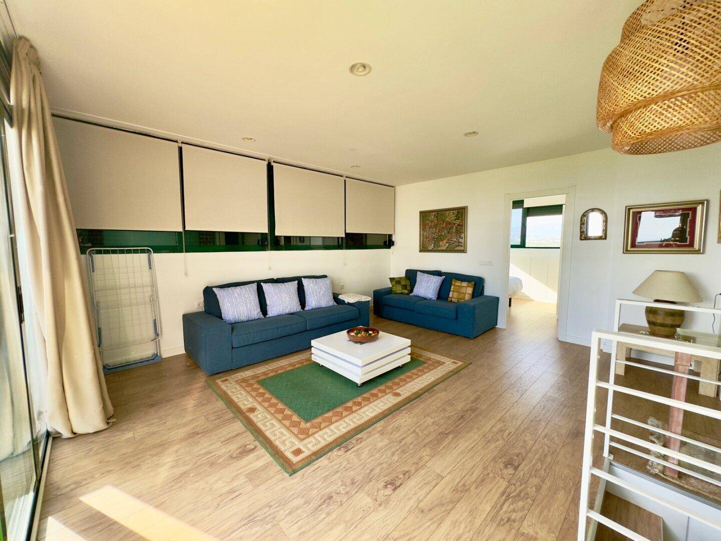 Helles Wohnzimmer mit blauen Sofas, Holzboden und Zugang zu einem Außenbereich.