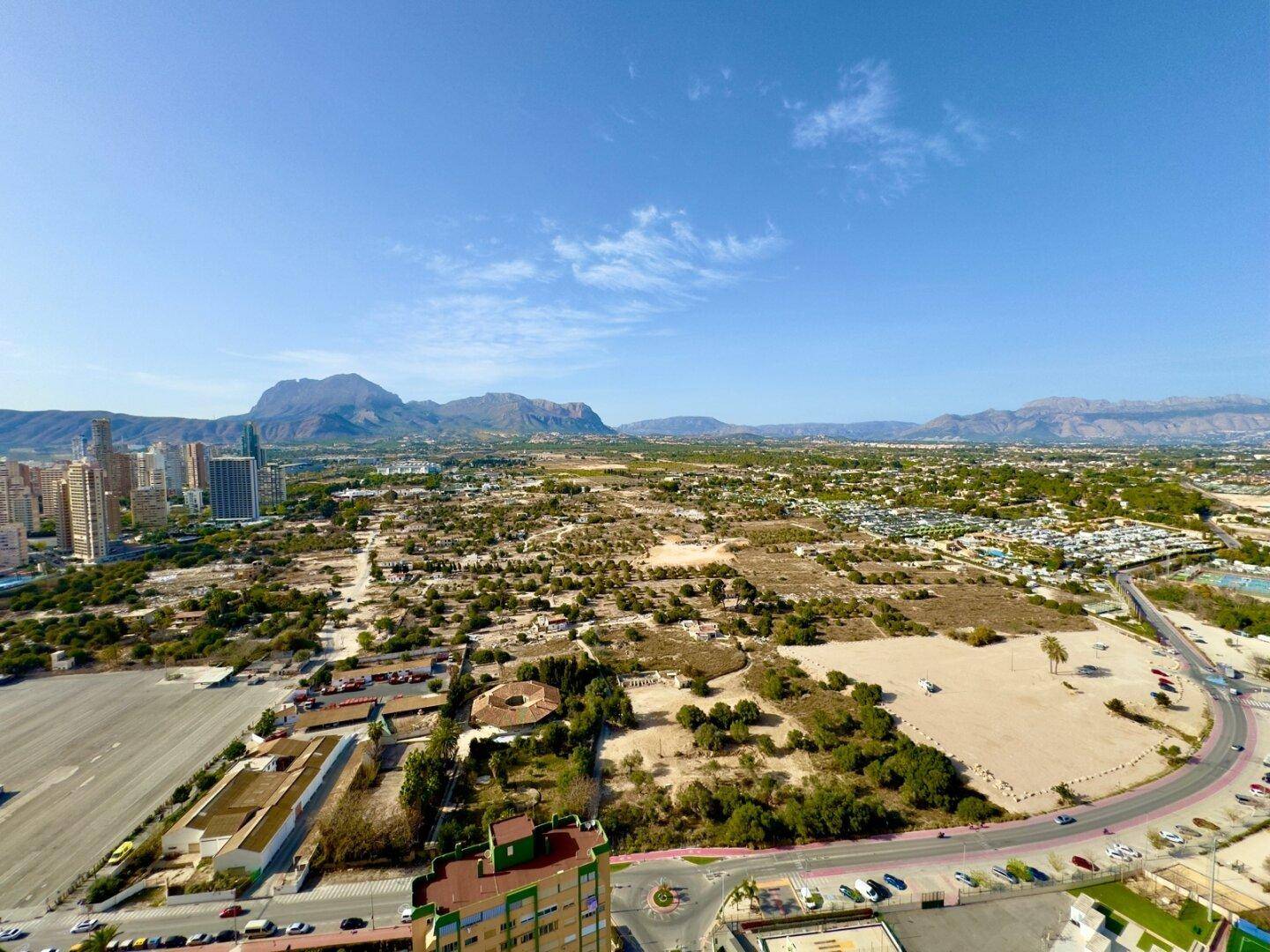Panoramablick auf die Stadt Benidorm mit weiten Grünflächen und majestätischen Bergen.