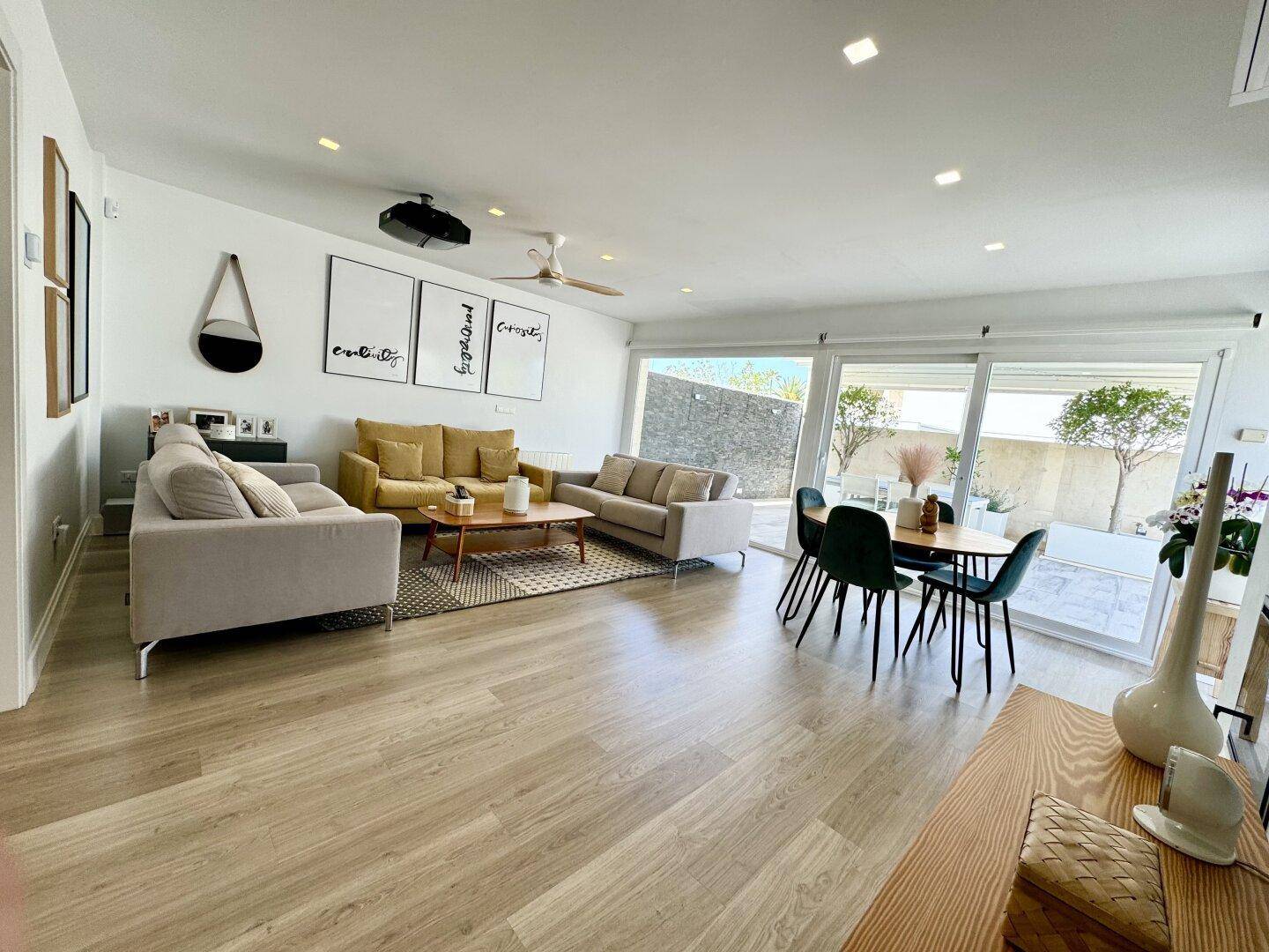 Heller offener Wohn-Essbereich mit modernem Interieur, Holzboden und Zugang zur Terrasse.