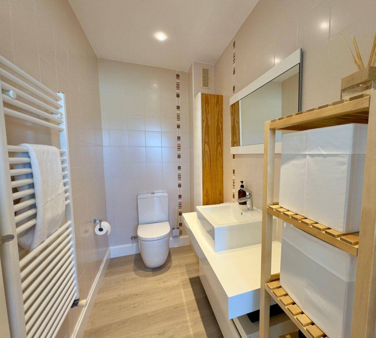 Helles Badezimmer mit Wand-WC, modernem Waschtisch und Fliesen an den Wänden.