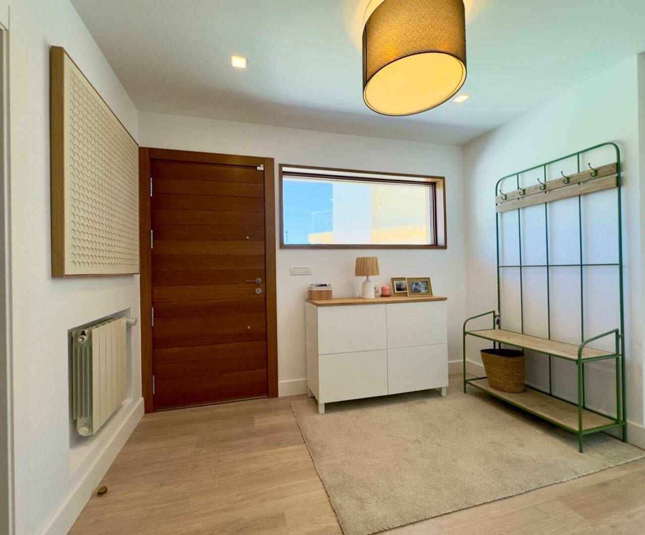 Einladender Eingangsbereich mit Holztür, Garderobe und heller Beleuchtung.