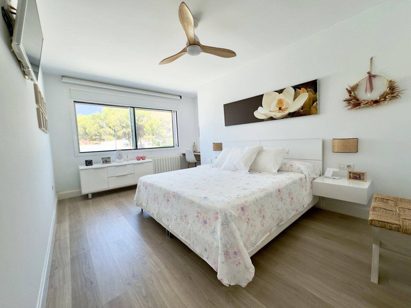 Geräumiges Schlafzimmer mit Doppelbett, Deckenventilator und großem Fenster mit Blick ins Grüne.