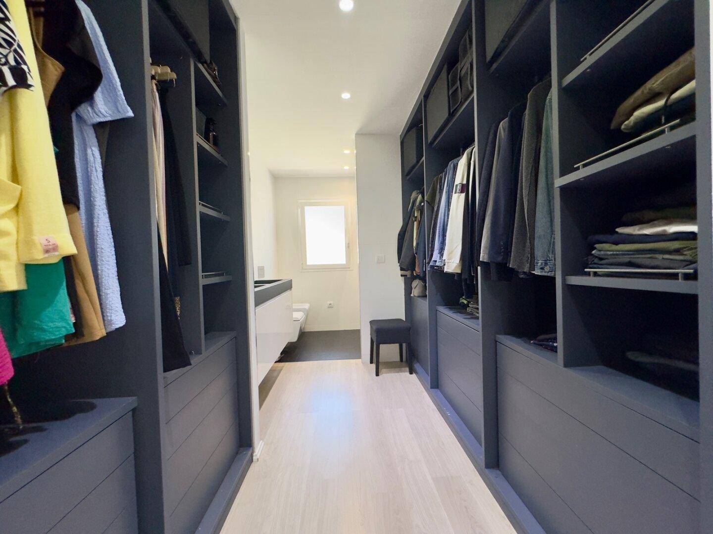 Begehbarer Kleiderschrank mit viel Stauraum und integrierten Schränken, der zum Badezimmer führt.