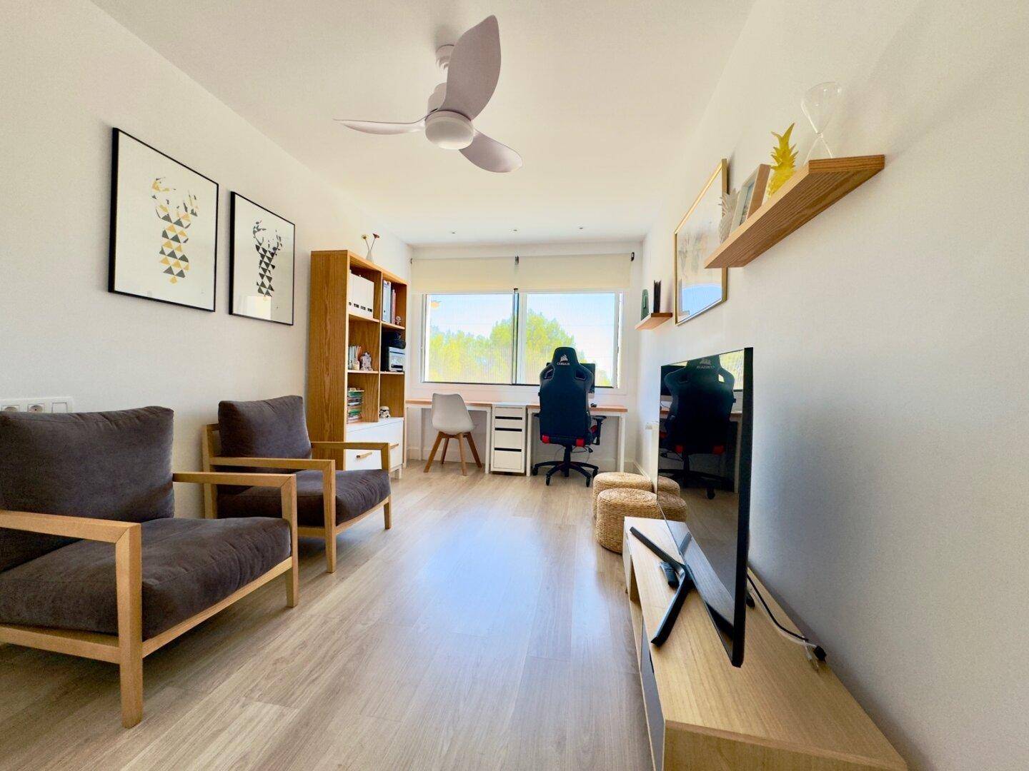 Helles Arbeitszimmer mit Schreibtisch, Bücherregal und bequemen Sesseln, ideal für Home-Office.