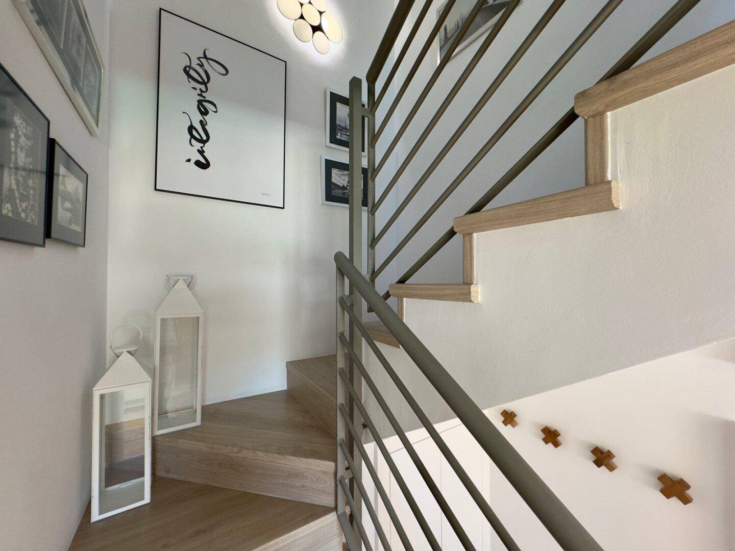 Moderne Treppe mit Holzstufen und elegantem Metallgeländer, verbindet die Etagen stilvoll.