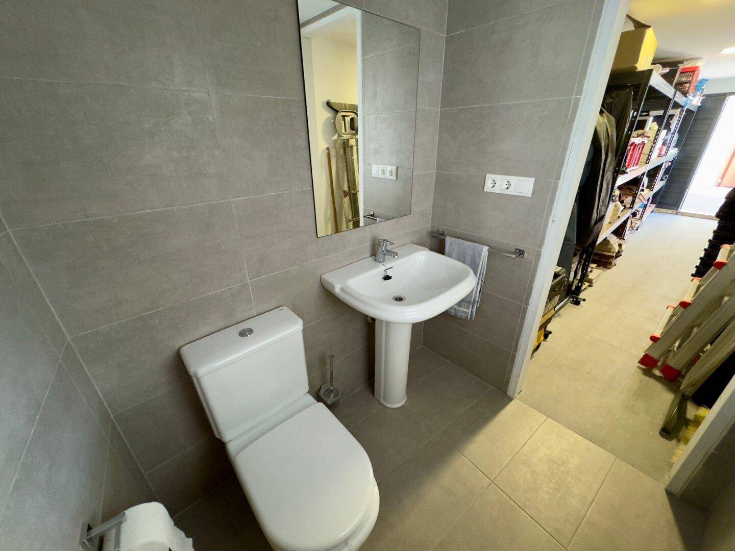 Kleines WC mit Standwaschbecken und Fliesen an den Wänden, praktisch und funktional.