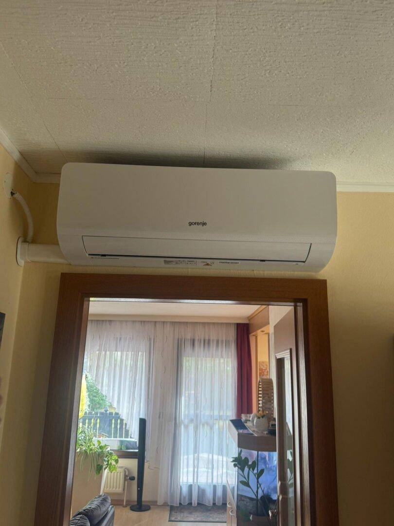 Innenraum mit einer Gorenje Klimaanlage über einem Türrahmen, der in einen Wohnbereich führt.