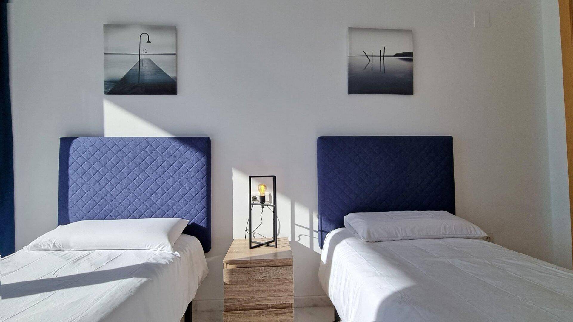 Schlafzimmer mit zwei Einzelbetten und moderner Wanddekoration, die eine ruhige Atmosphäre schafft.