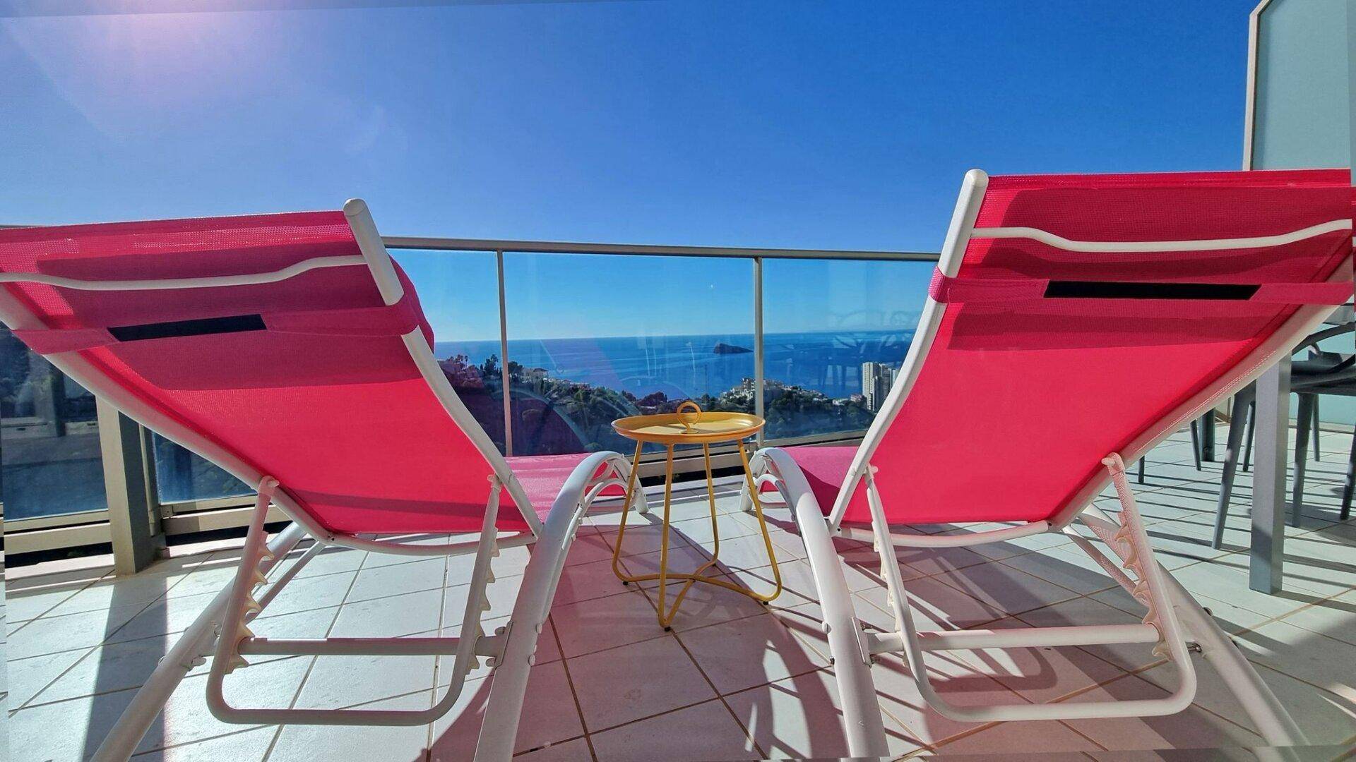 Zwei bequeme Liegestühle auf dem Balkon laden zum Entspannen mit Panoramablick auf das Meer ein.