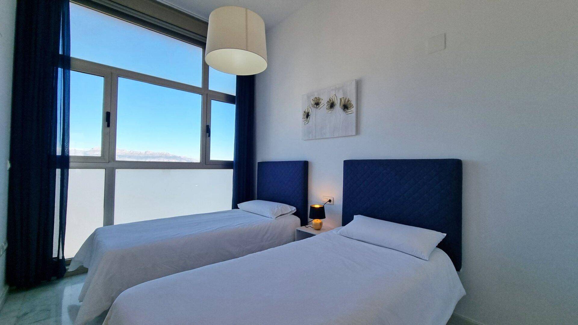 Gemütliches Schlafzimmer mit zwei Einzelbetten und großen Fenstern für eine helle Atmosphäre.
