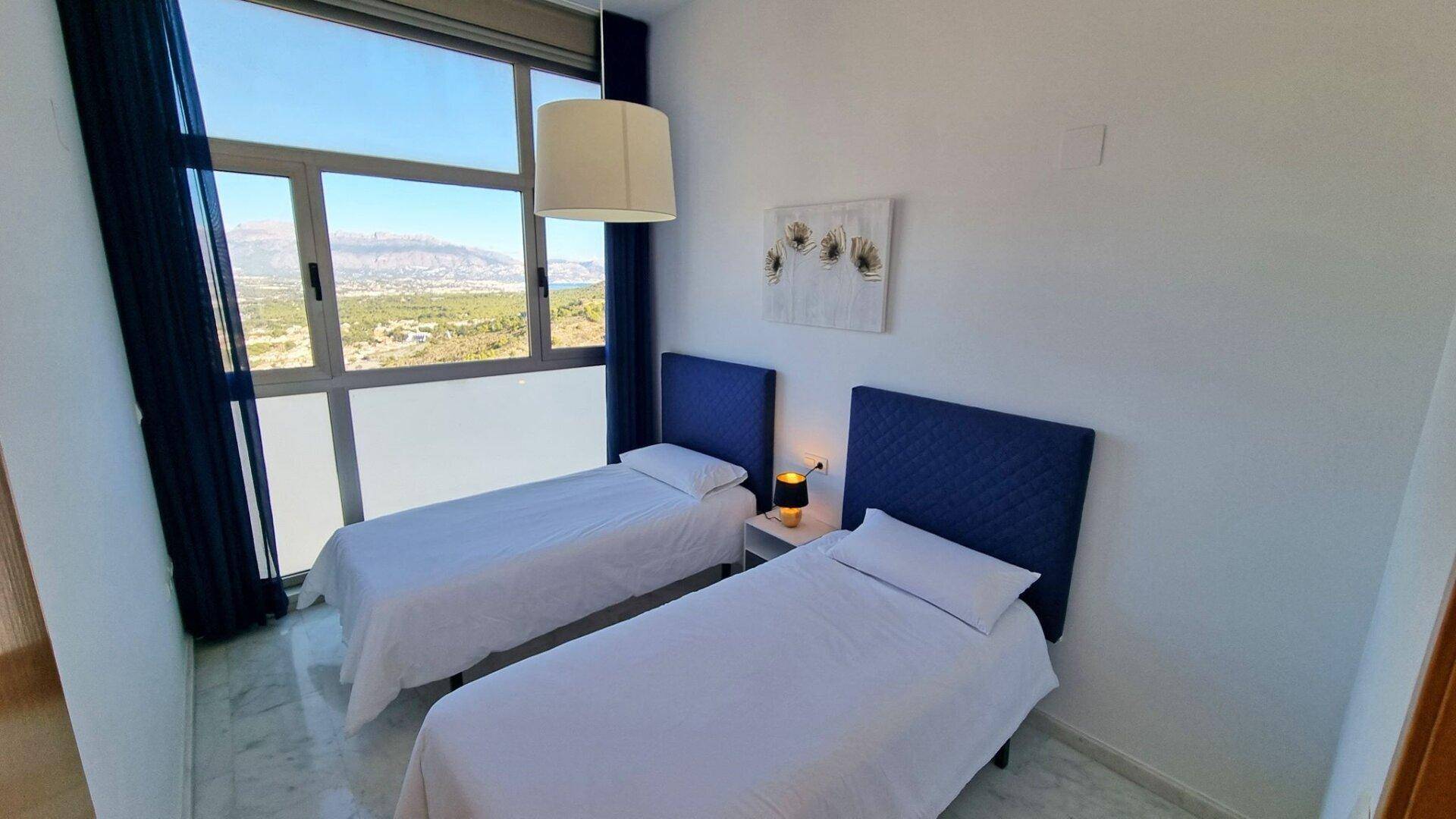 Schlafzimmer mit zwei Einzelbetten, großen Fenstern und einem angenehmen Blick ins Grüne.