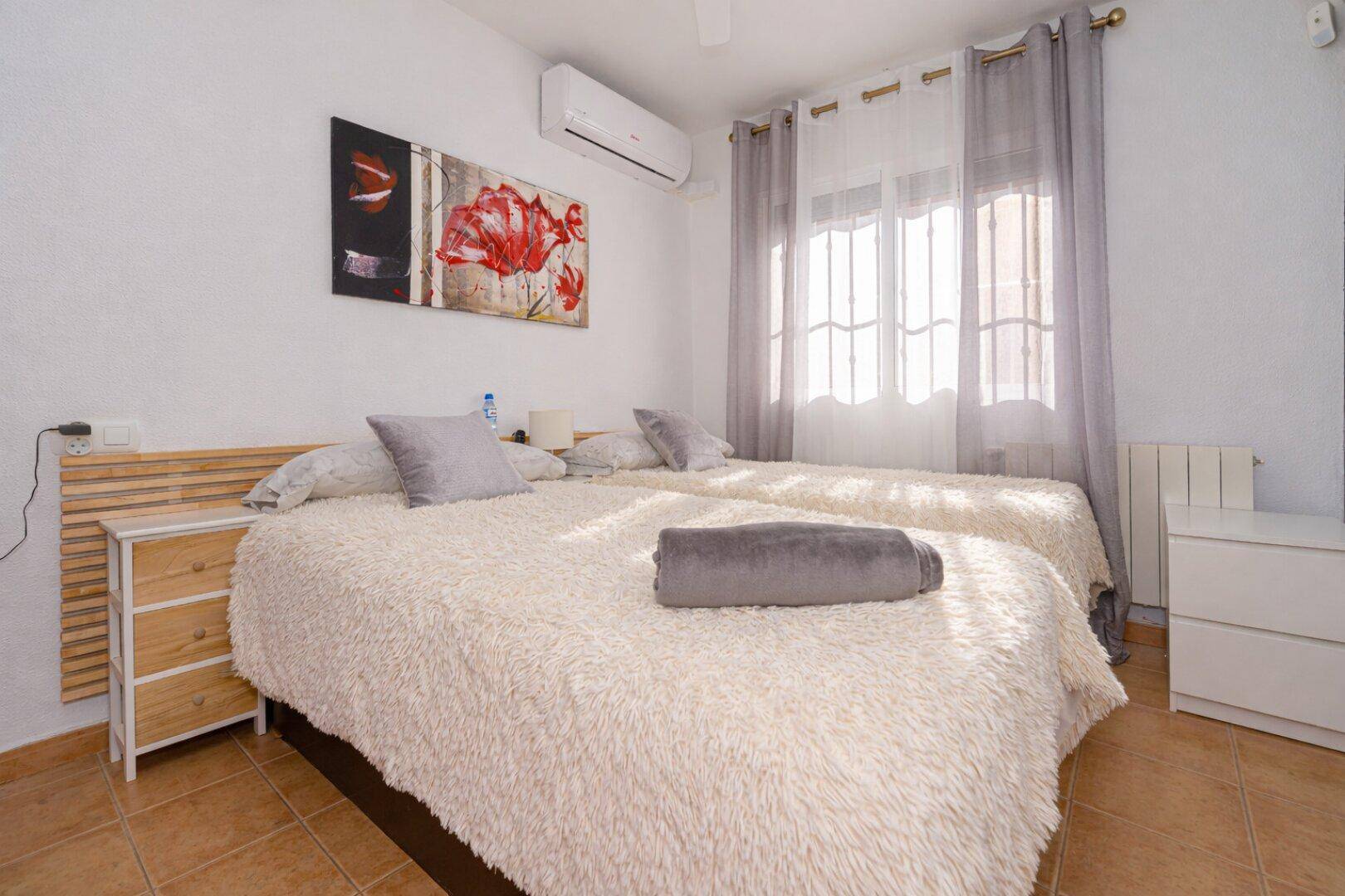 Schlafzimmer mit zwei Einzelbetten, Klimaanlage und Terrakottafliesen, hell und komfortabel.