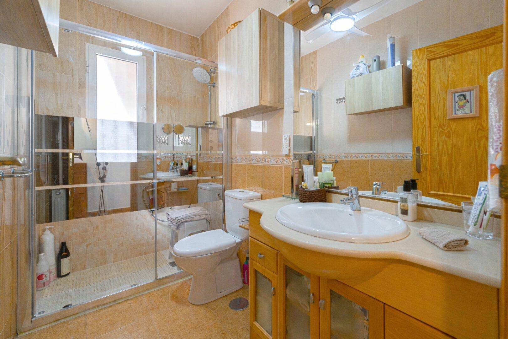Badezimmer mit Dusche, Fenster und Holzwaschtisch, funktional und hell.