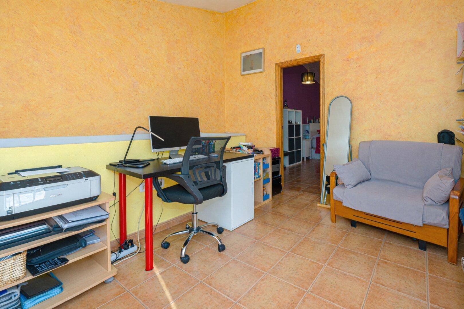 Dachzimmer als Büro eingerichtet mit Schreibtisch, Computer und gelben Wänden.